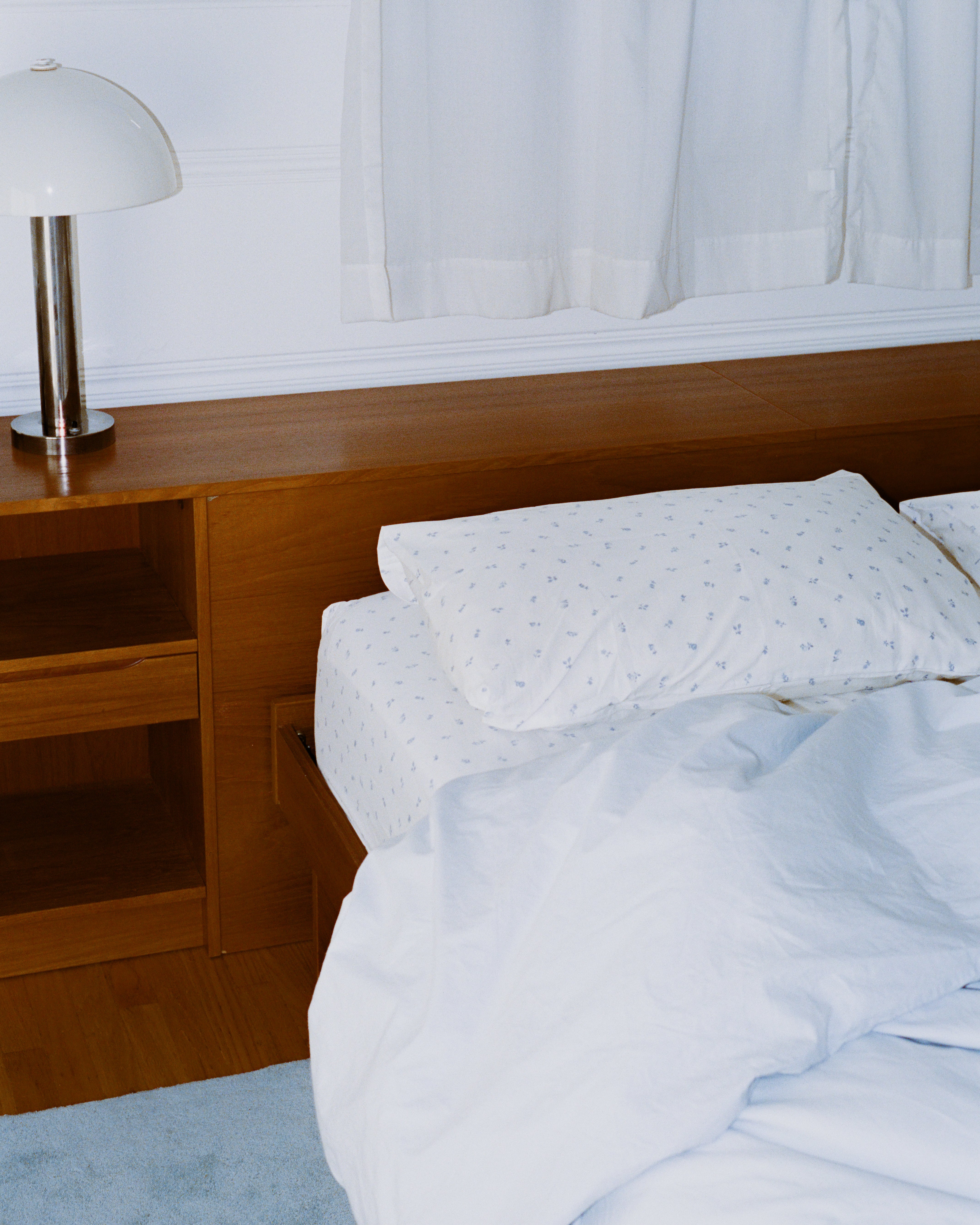 Bed with blue floral bedding and pillows and blue duvet.